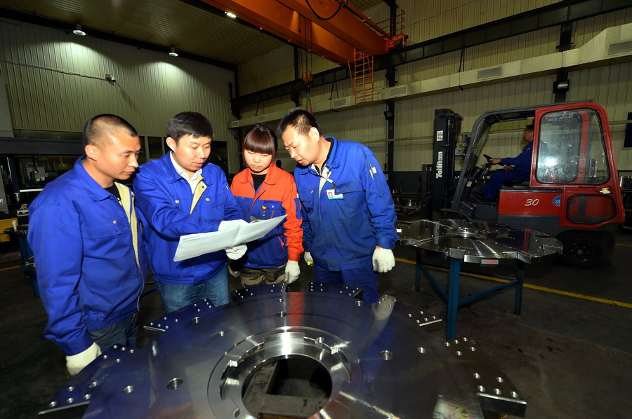 王钦峰（左二）与工友一起研究轮胎模具图纸（4月17日摄）。新华社记者 范长国 摄